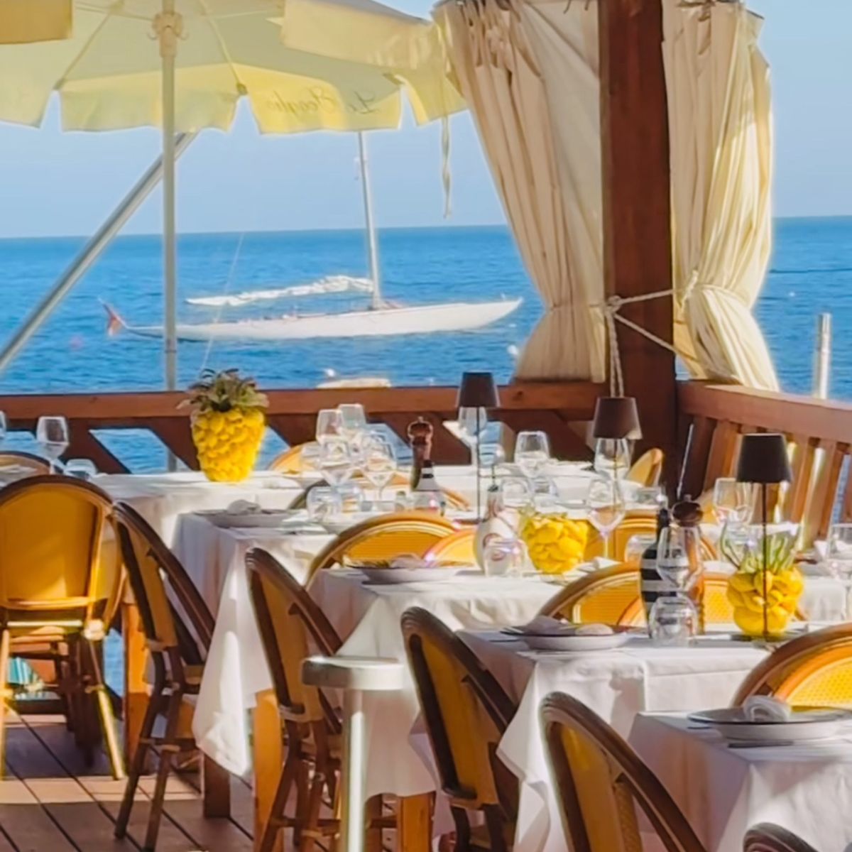 outdoor dining table with chairs next to the sea