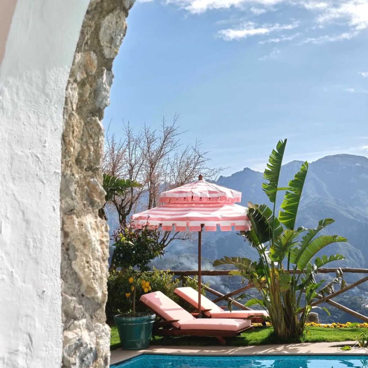 pink sun chairs and umbrellas with the mountains in the background