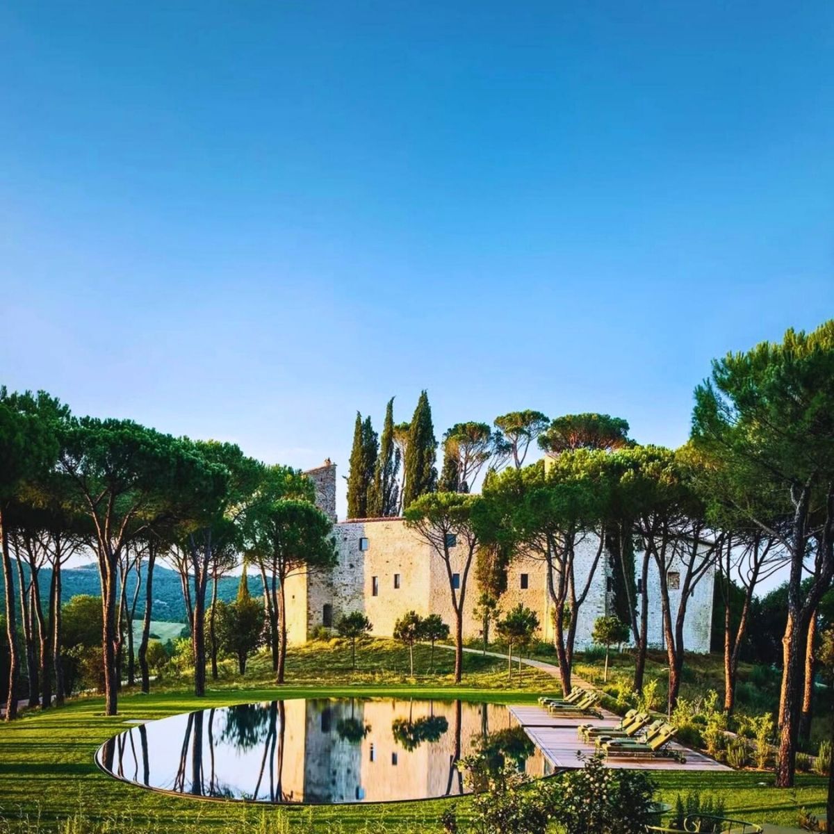 an outdoor pool surrounded by trees and a castle in the background