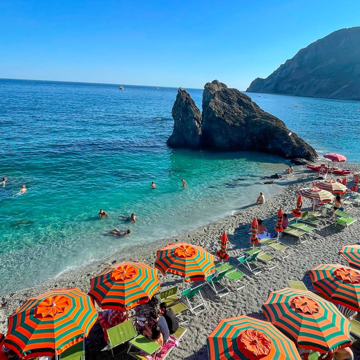 sandy beach with orange beach umbrellas in cinque terre