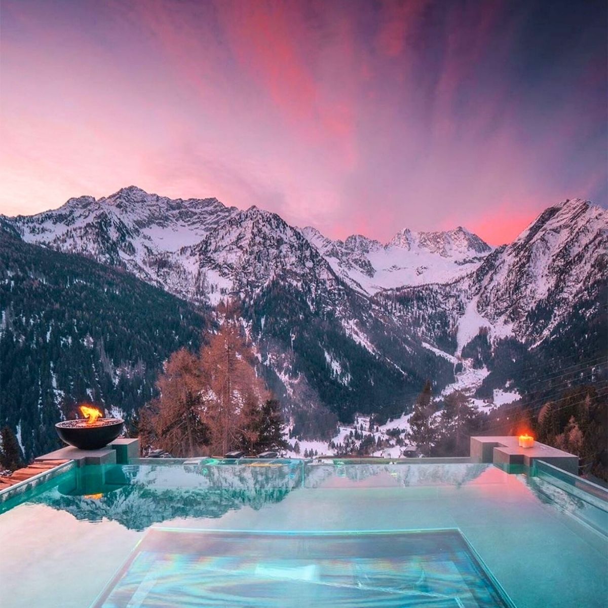 pool overlooking a pink sky and snowy mountains in the Dolomites