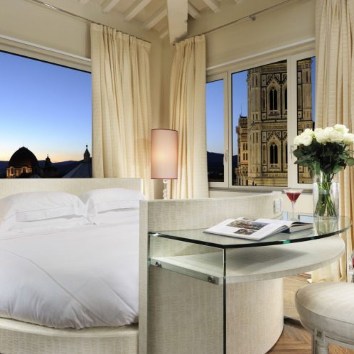 hotel room with a white bed and windows overlooking to Duomo in Florence