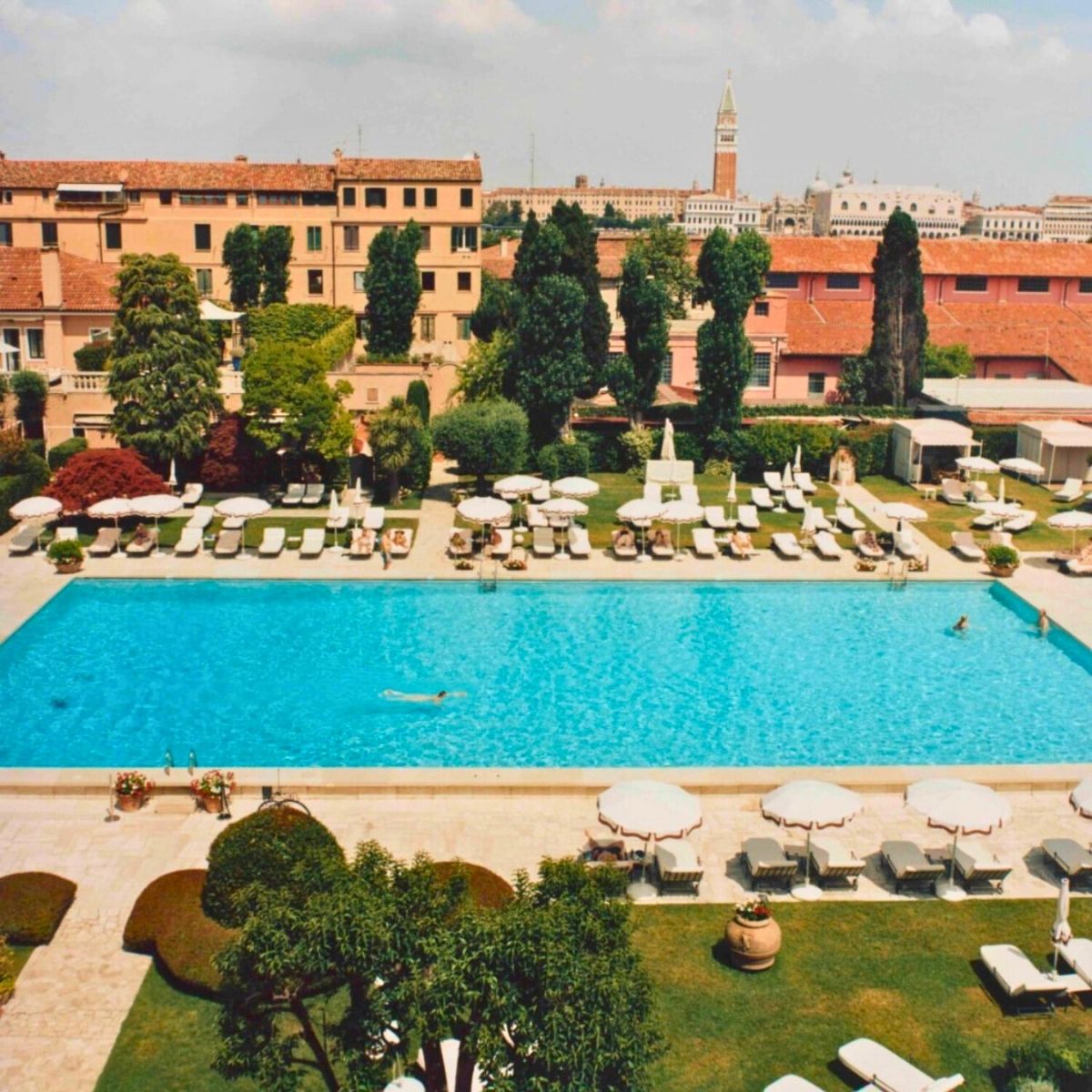 large swimming pool with a coral hotel building in the background