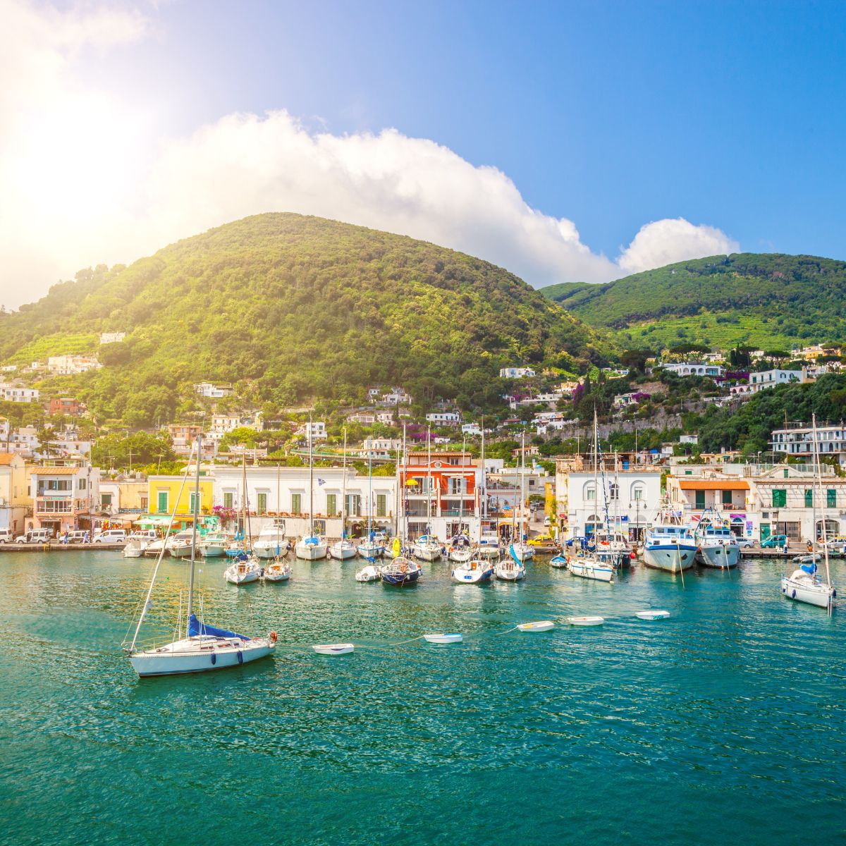sail boats in the sea with the the town of ischia in the background