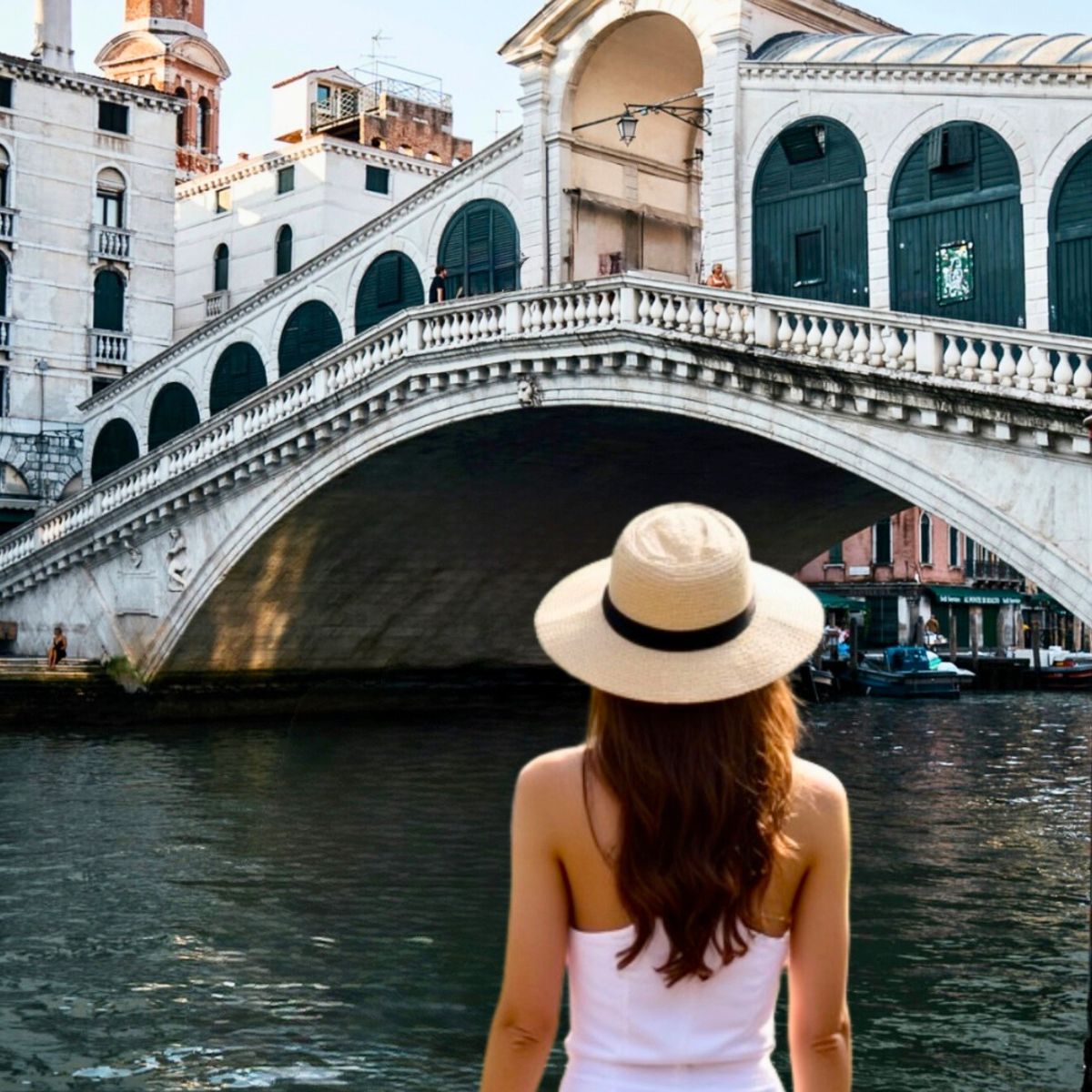 female wearing a sunhat facing the Rialto Bridge in Venice