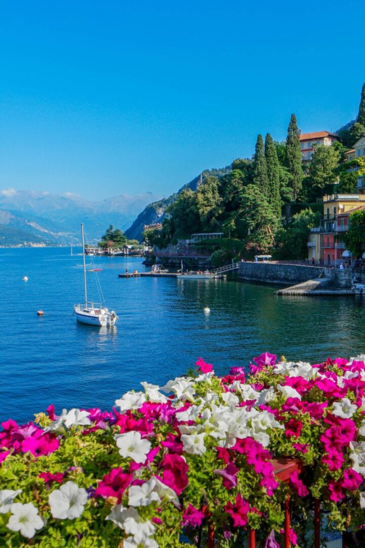 lake como sparkling in the sun with a sail boat and mountains in the background