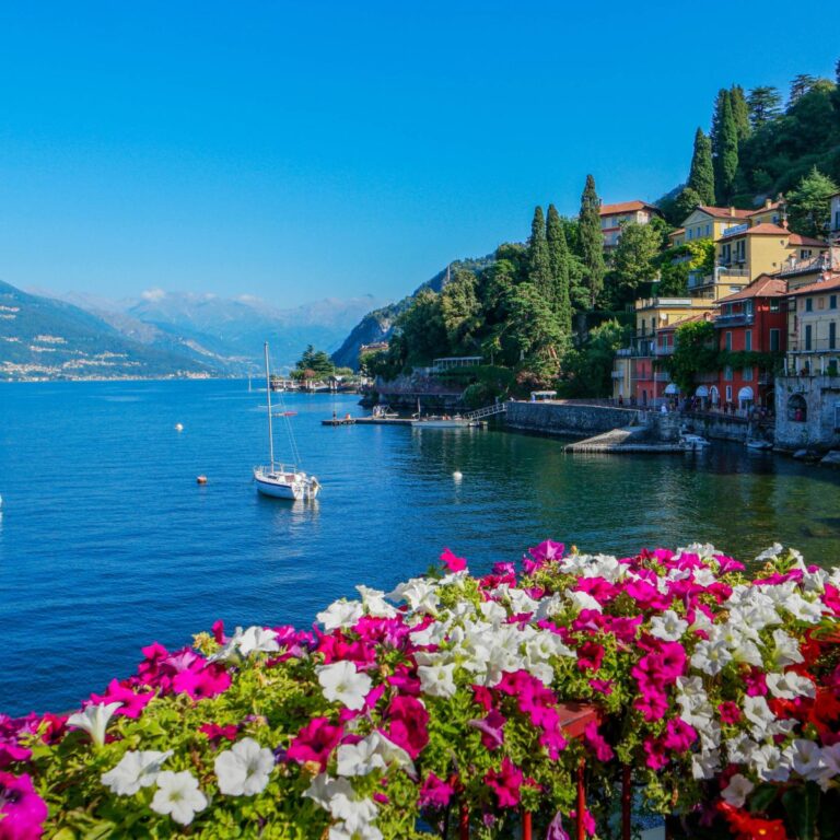 lake como sparkling in the sun with a sail boat and mountains in the background