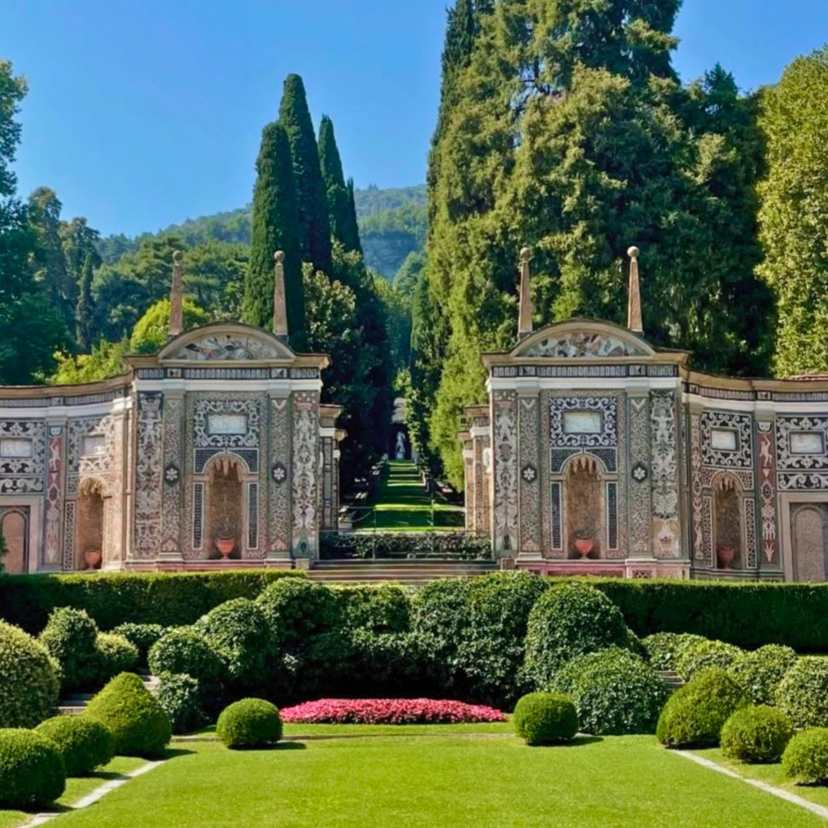 villa garden with green grass, bushes, and stone wall