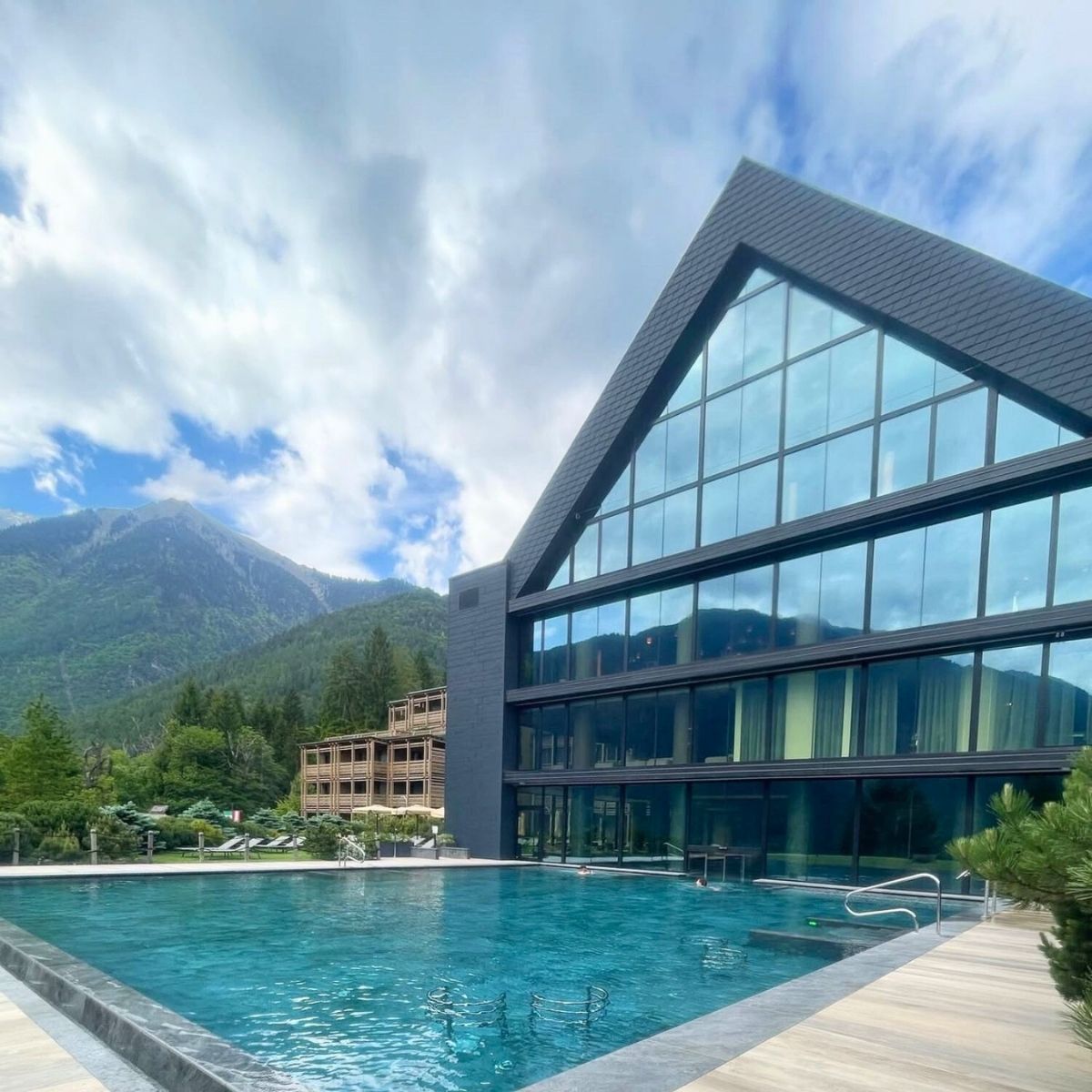 outdoor swimming pool in the mountains with back glass building 