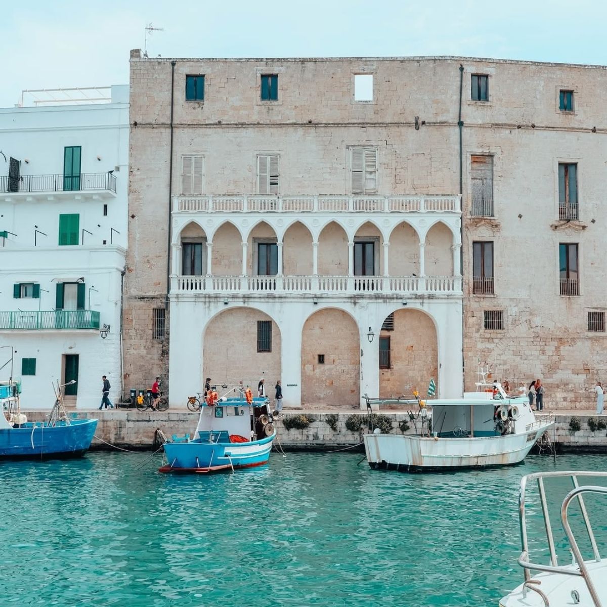 harbor with fishing boats and stone building along it