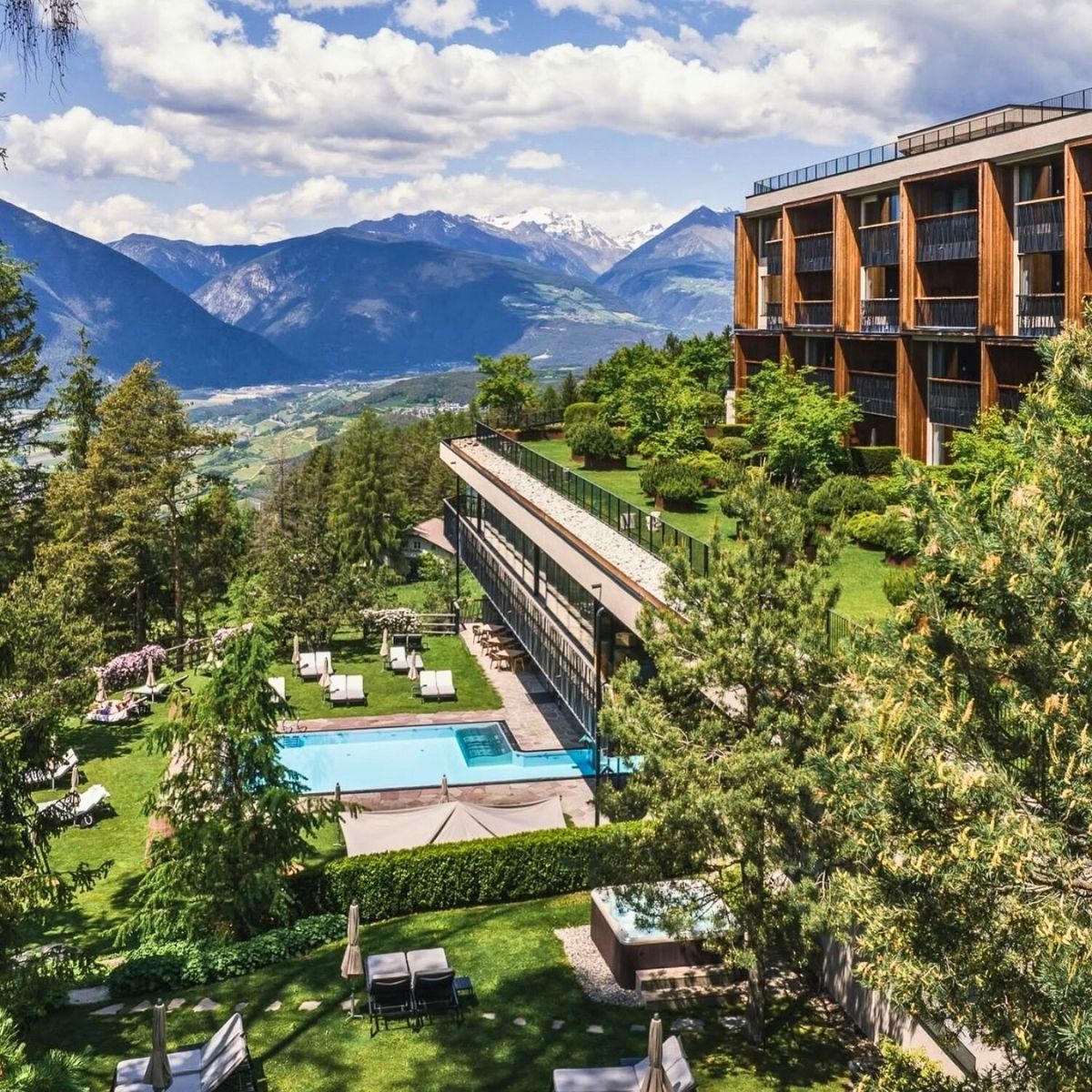 overhead shot of lodge with swimming pool with green trees and mountains in the background