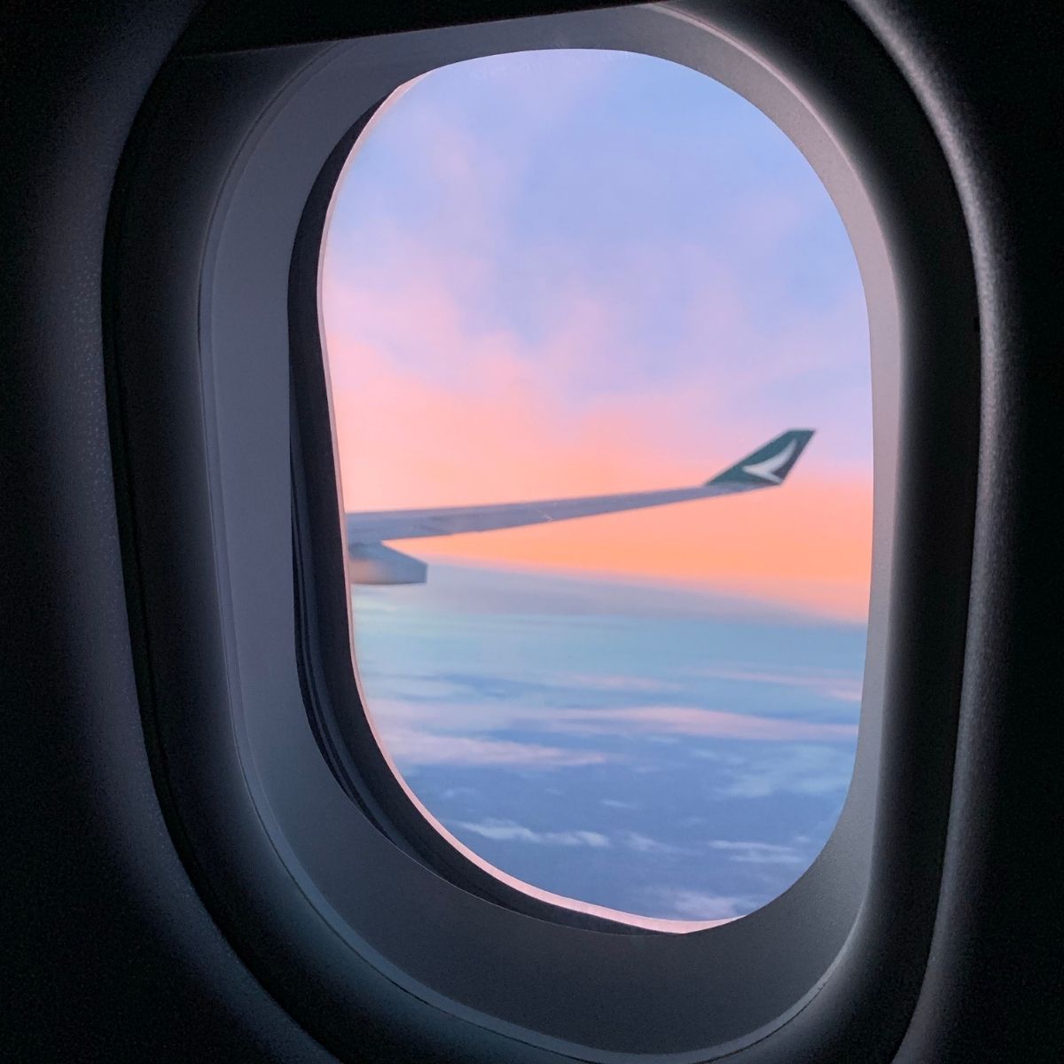 plane window looking onto sunset and clouds