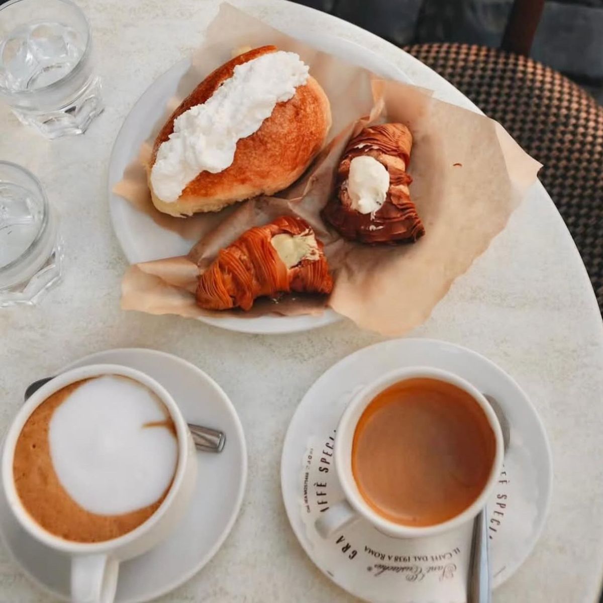 overhead shot of two coffee and a plate of croissants