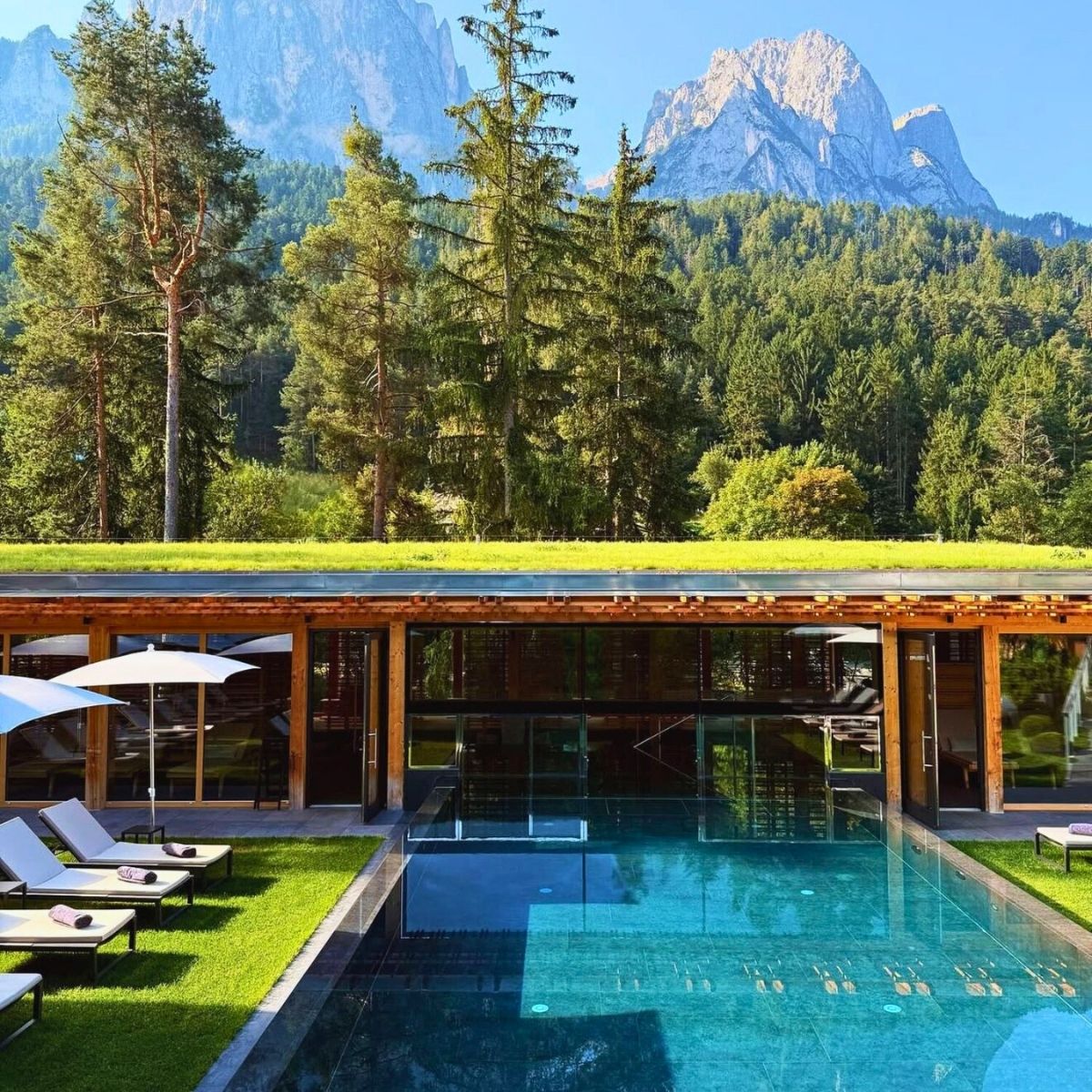 swimming pool with wooden building and mountains in the background
