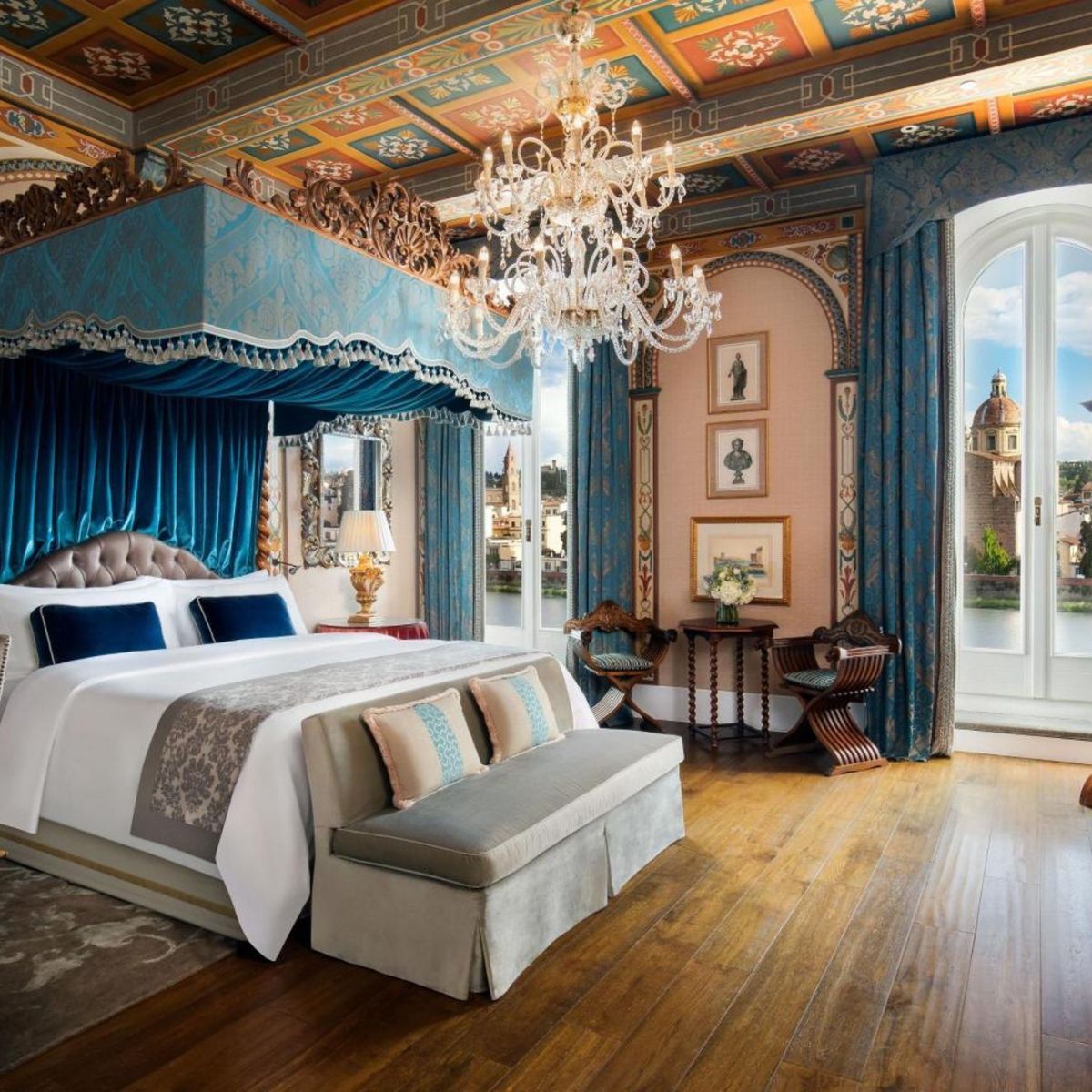 hotel room with a large bed with blue canopy and a chandler  