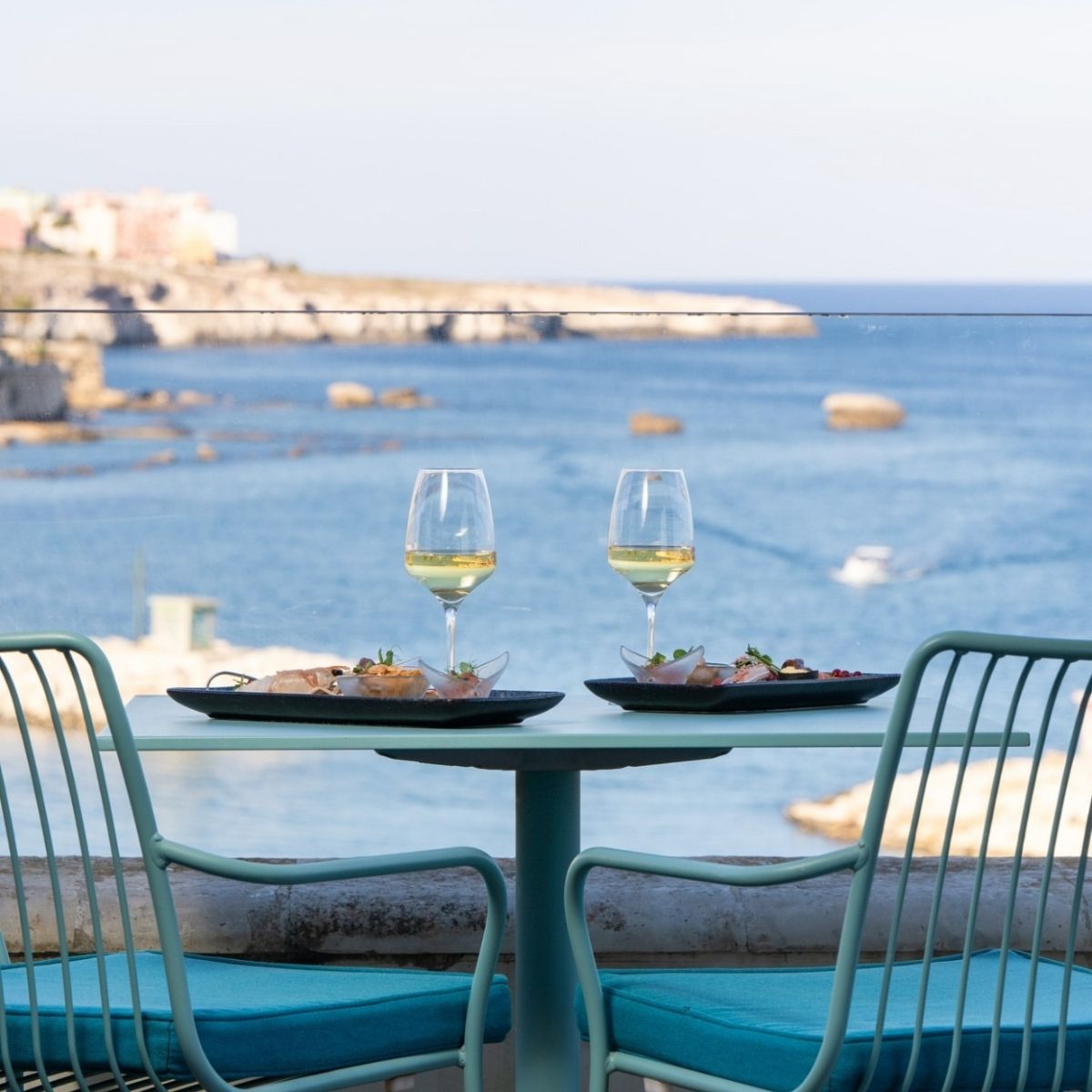 dining table with 2 glasses of wine overlooking the sea