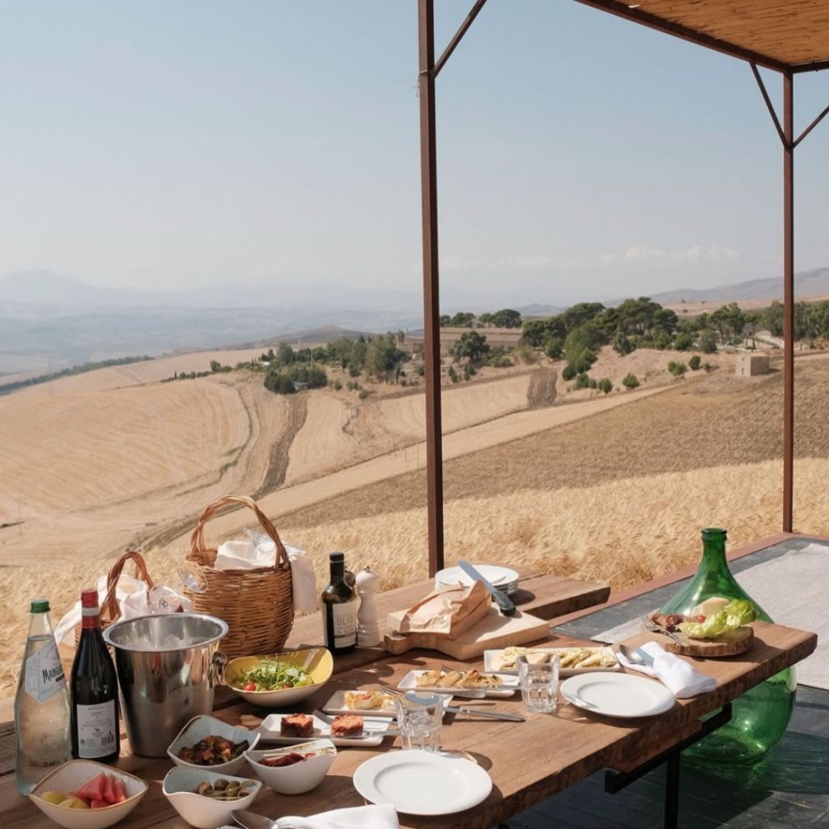 table with food and drinks overlooking a valley with brown grass