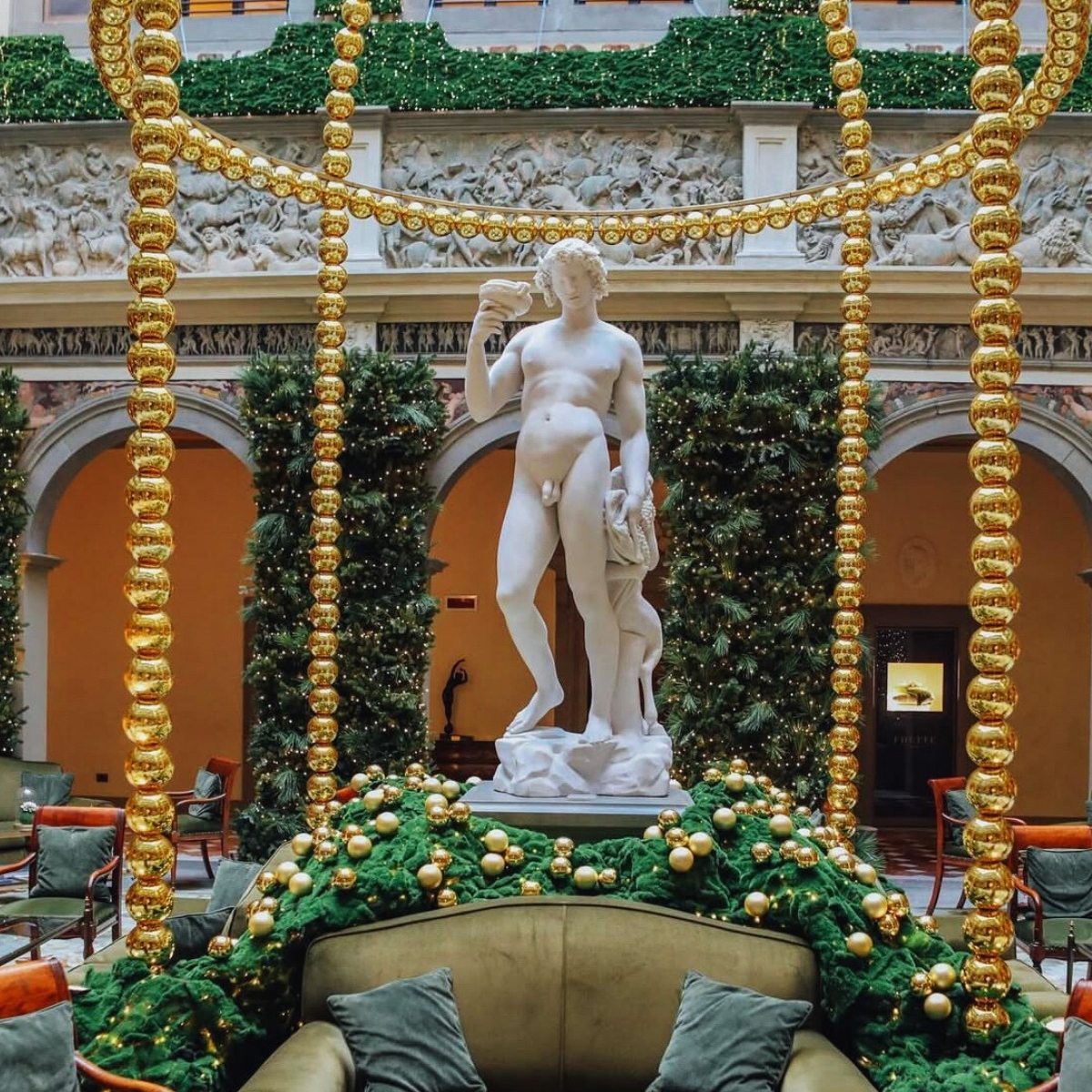 status of david surrounded by gold ornaments and green pine