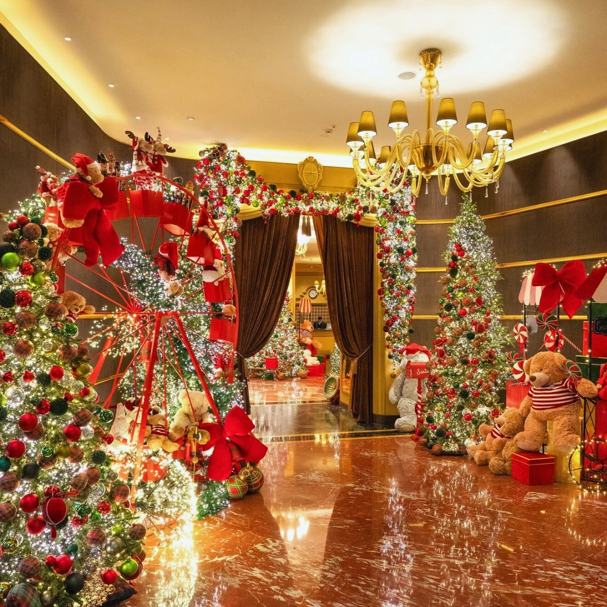 multiple christmas trees in a hotel lobby with a gold chandelier