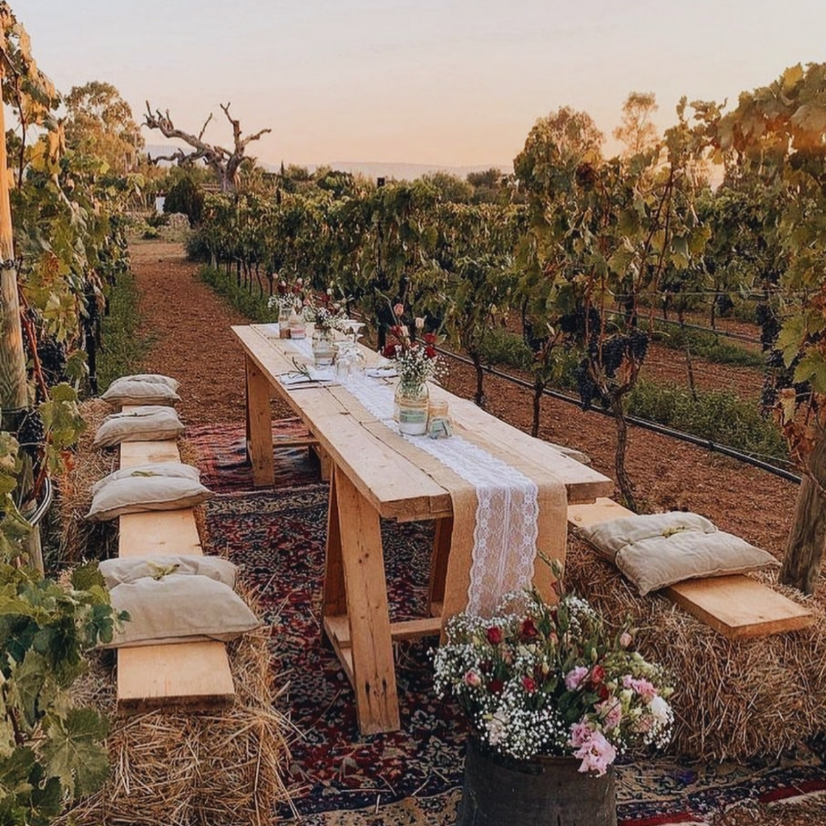 outdoor wood table in vineyard with red flowers