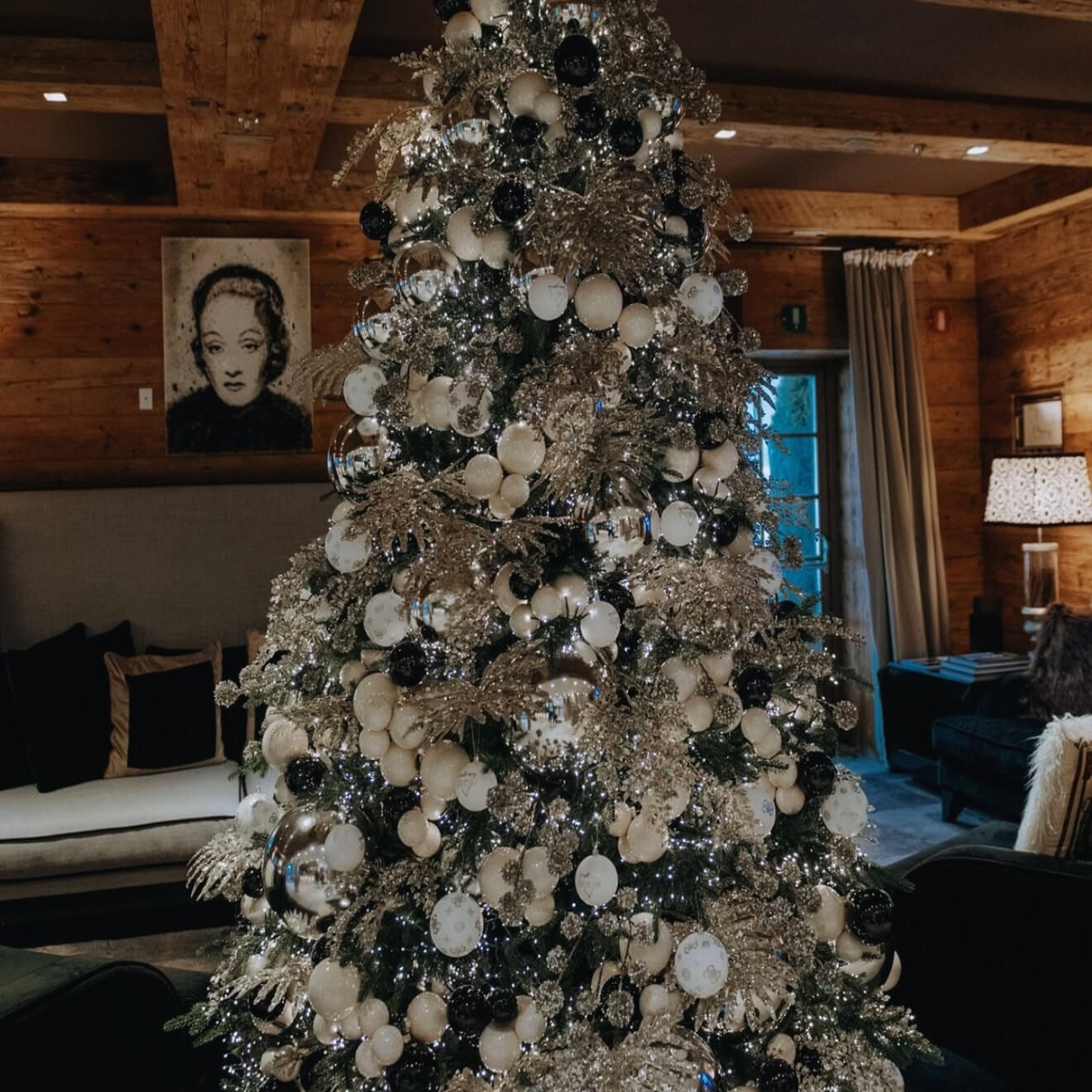 christmas tree with white and gold ornaments in a log cabin
