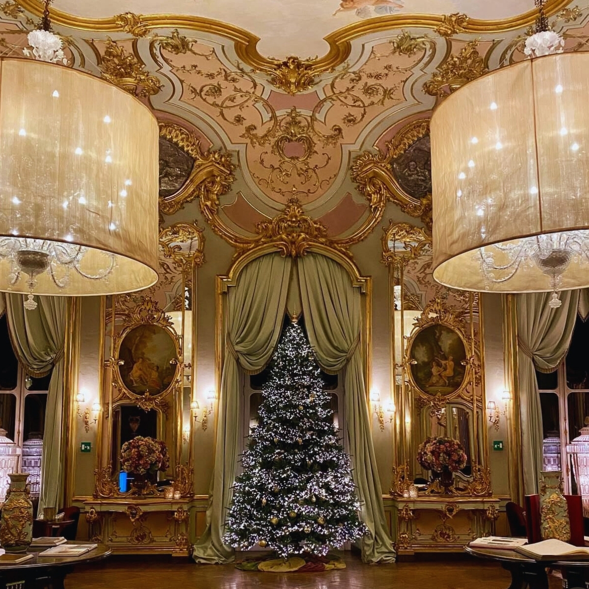 ornate room with gold and pink moulding with christmas tree in center