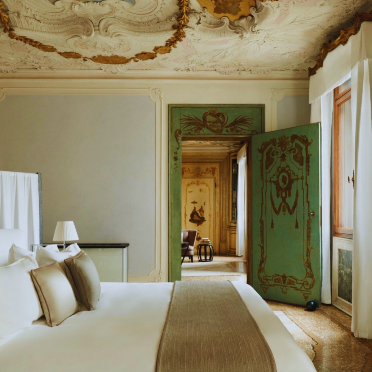 A luxurious hotel bedroom featuring an ornate ceiling, elegant furnishings, and a serene atmosphere at Aman Venice