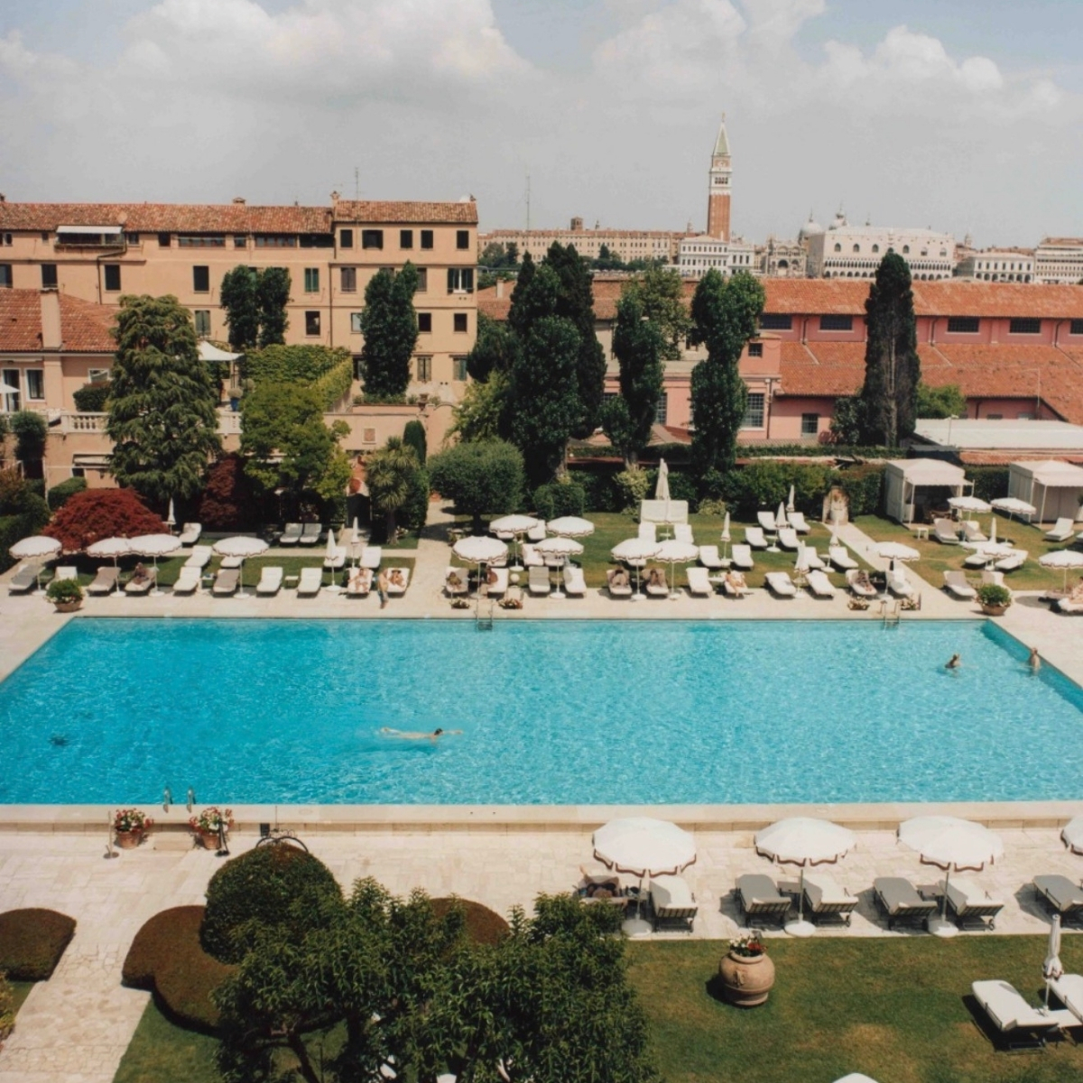 Scenic view of a luxurious hotel pool with sun loungers and lush greenery in Venice, Italy at Belmond Hotel Cipriani